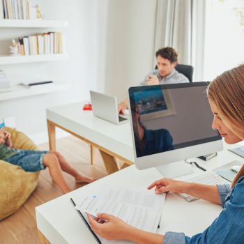 a family sit together in their home office making use of social networking and computer technology