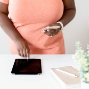 Woman tapping tablet while holding phone