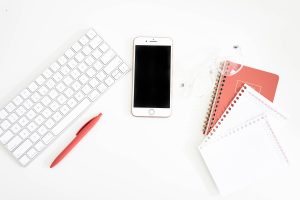 Notebook and iphone sitting next to keyboard