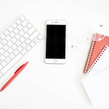 Notebook and iphone sitting next to keyboard