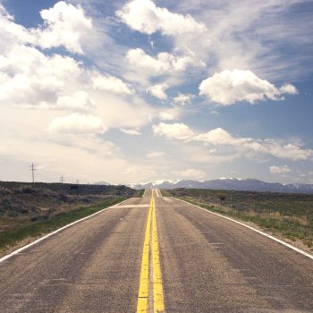 photo showing blue skies and a long endless road